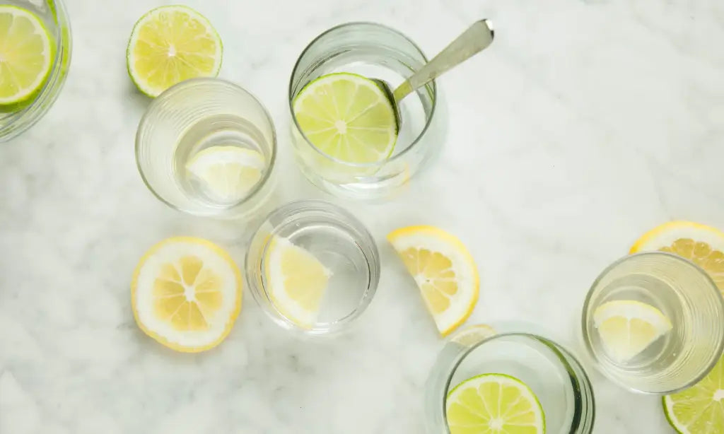 Photo de verres d'eau avec des citrons jaune et vert utilisé comme illustration pour donner le conseil suivant "L'acidité du citron ralentit la digestion et permet d'éviter les pics de glycémie. Nous vous recommandons de consommer avant chaque repas un jus de citron frais, dilué dans un verre d'eau et accompagné de Mira®."